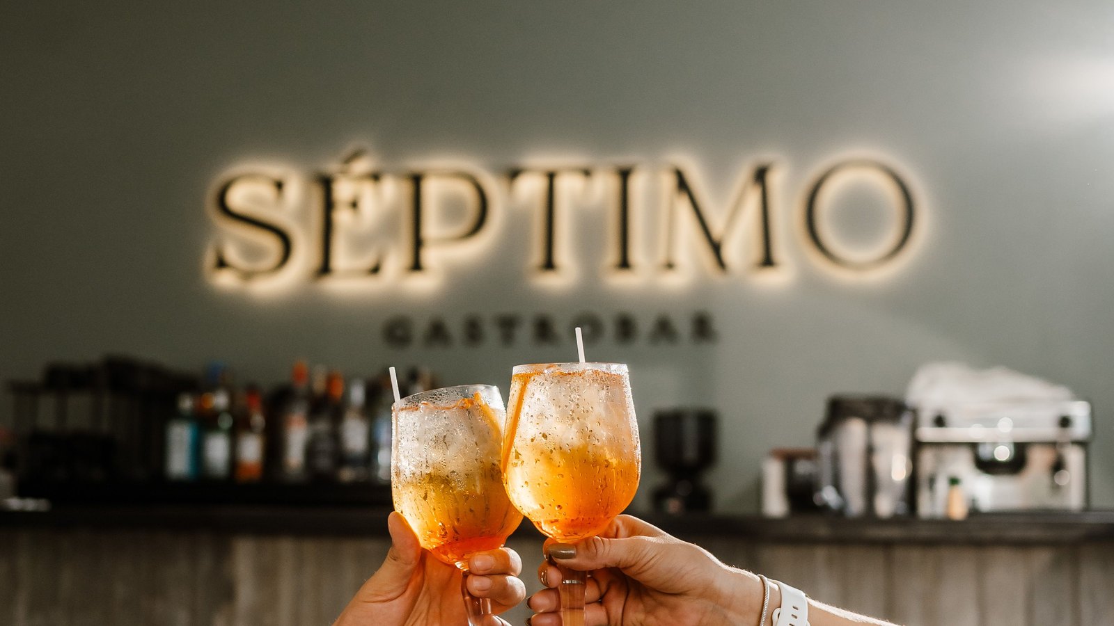 Séptimo Gastrobar, el rooftop bar de Suites Las Palmas: rótulo iluminado sobre la barra y dos copas brindando